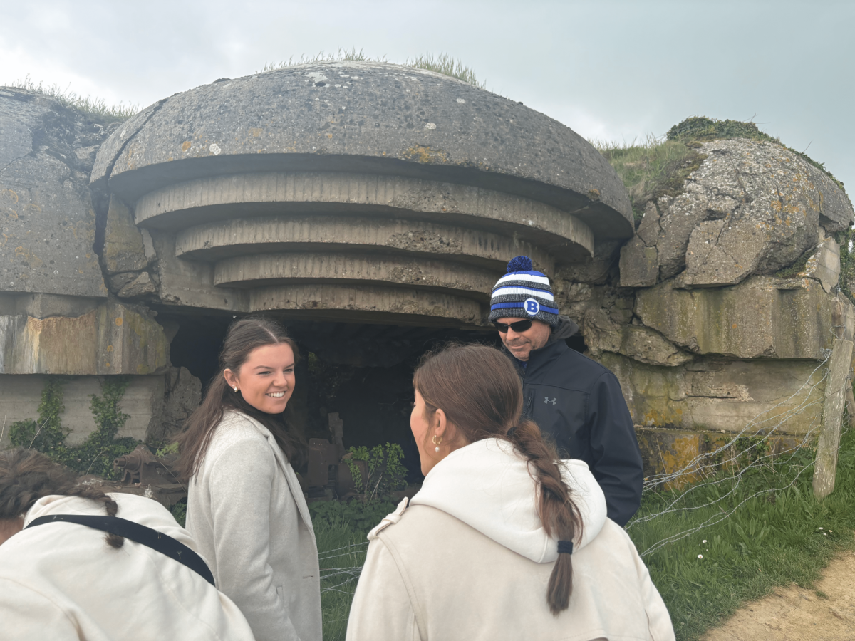 Braintree High students Ali and Sophia, and teacher Mr. Flanagan at the D-Day beaches looking and talking about the bomb shelter. 