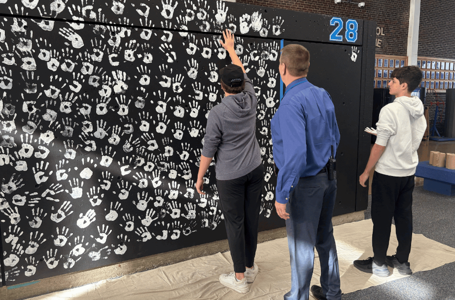 Members of the class of 2028 leave their handprint on the wall in the gym lobby. 