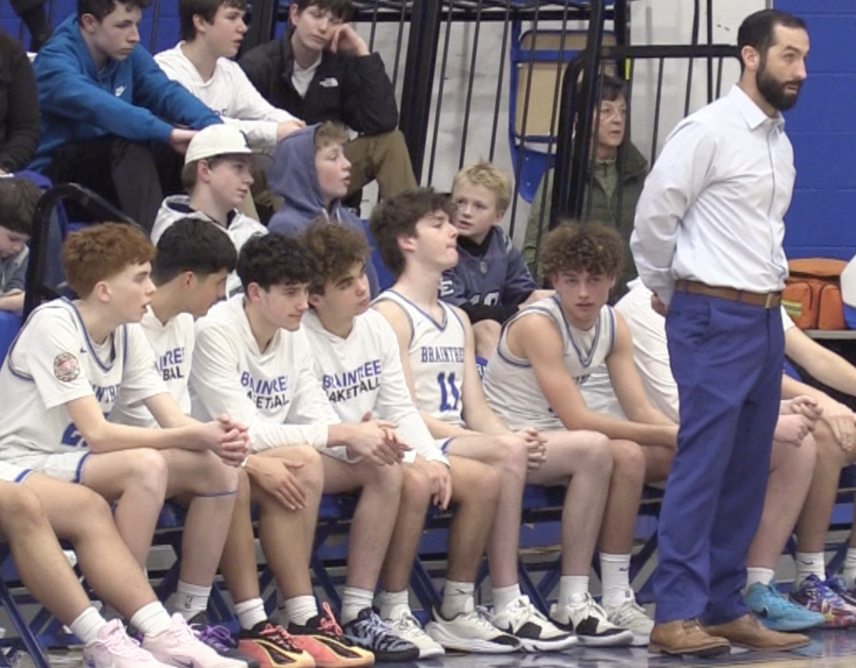 Coach Wall stands by his team while spectating a basketball game. 