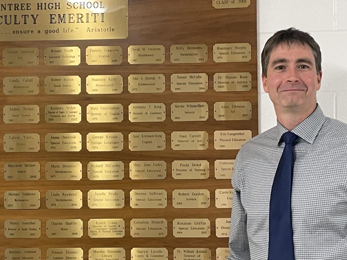 Dr. Fitzgerald poses next to the Braintree High School Faculty Emereti Sign outside the principal's office.
